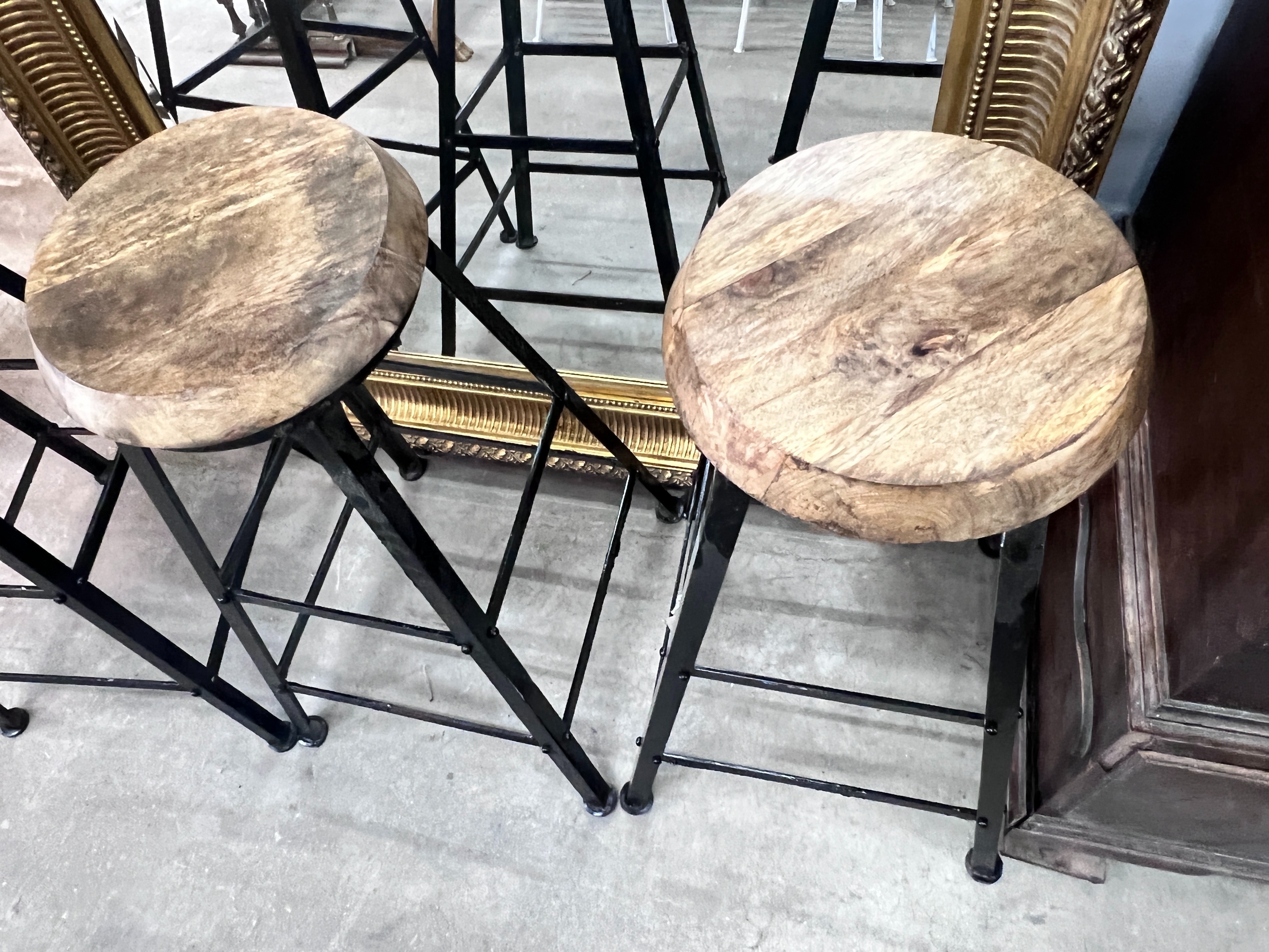 A set of four industrial style painted wrought iron bar stools with circular wooden seats, height 80cm